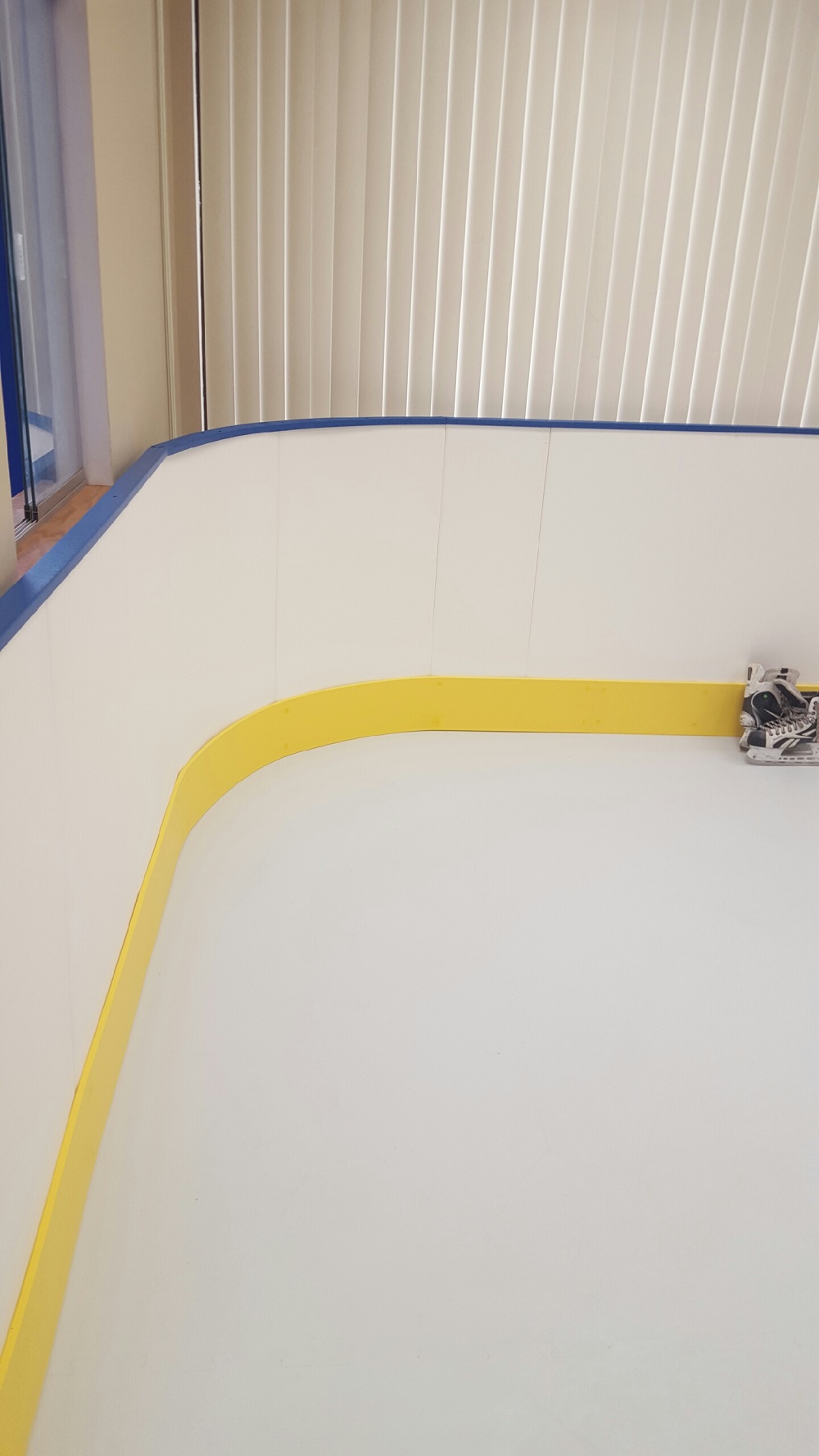 Synthetic ice rink with rounded corners.  42 inch tall white boards with yellow kicker.